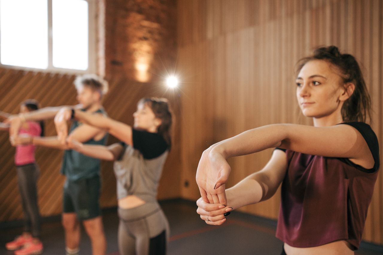 class-04 Individuals stretching during a fitness class in a gym setting, promoting group exercise.