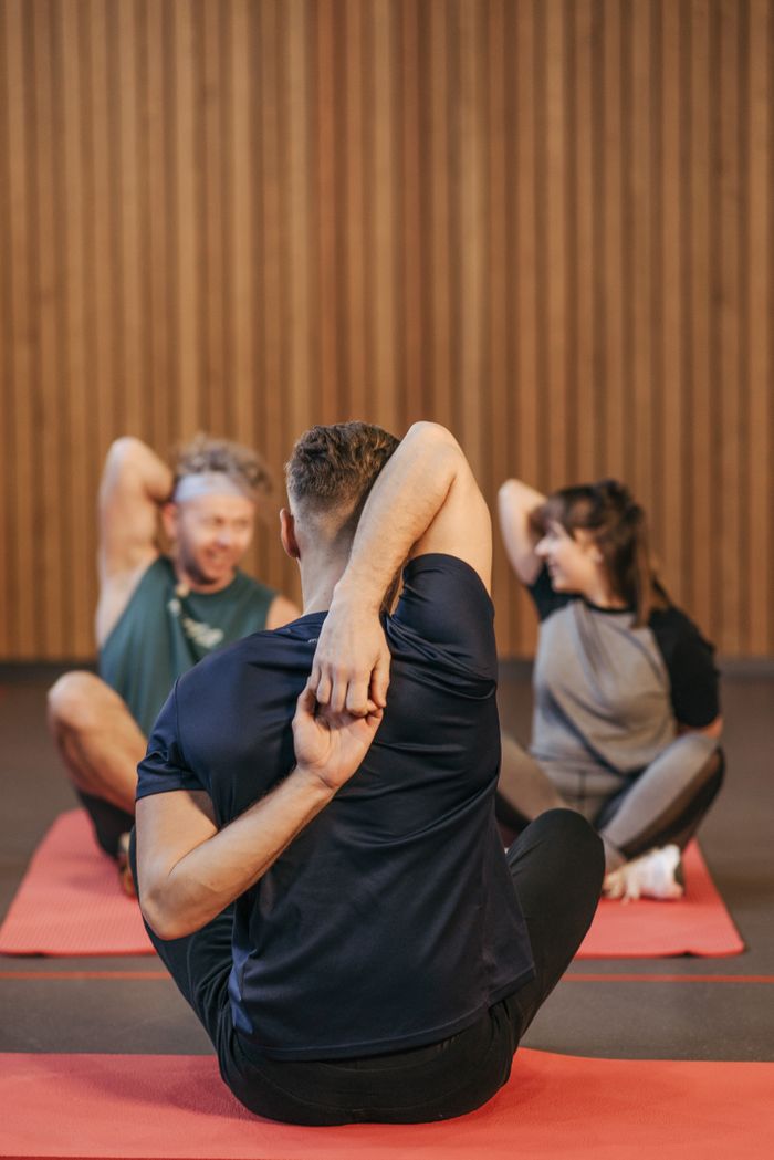 our-mission Adults in activewear practicing yoga and stretching indoors on mats.