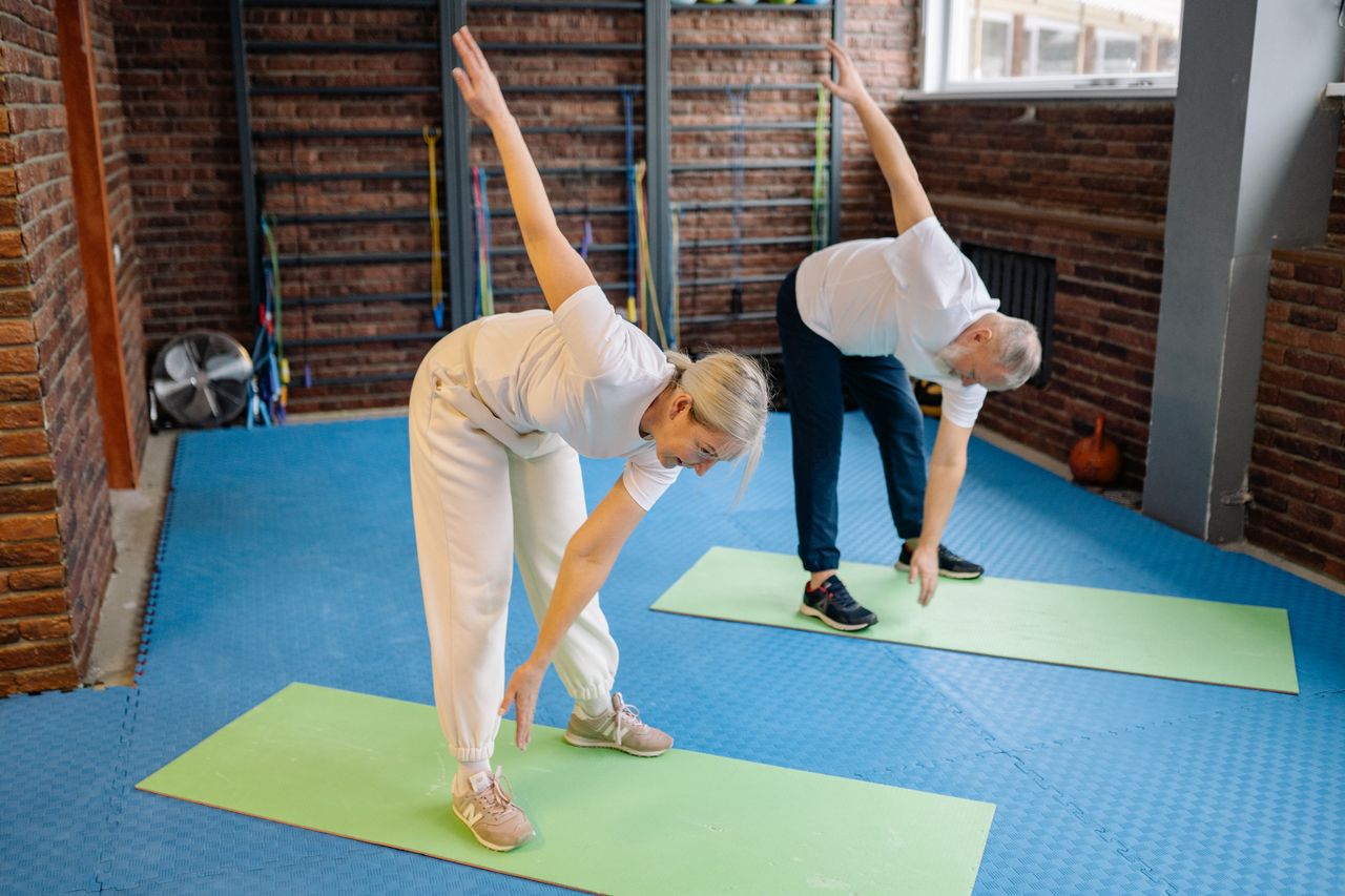 Crafting Captivating Headlines: Your awesome post title goes here Active senior couple performing stretching exercises on mats in a modern fitness gym.