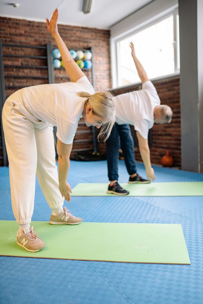 our-approach Senior adults stretch on mats in a fitness gym, promoting a healthy lifestyle.