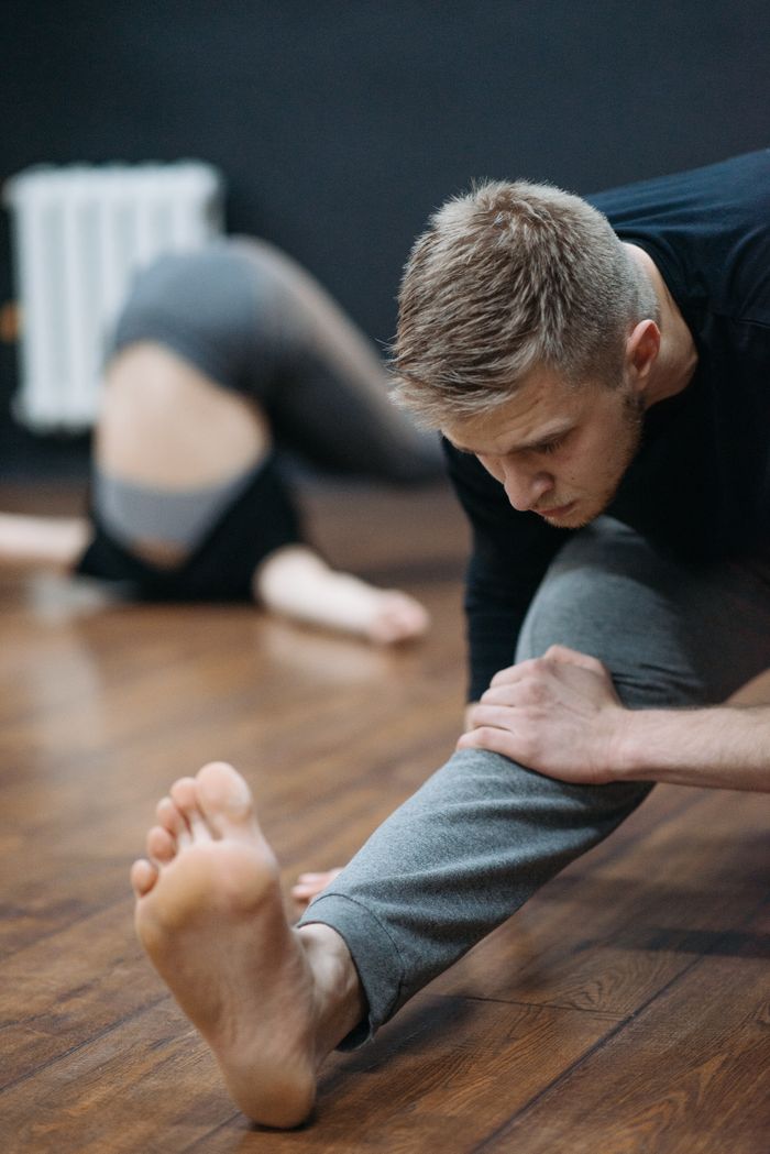 our-story A man stretches in a gym setting, focusing on flexibility and fitness.