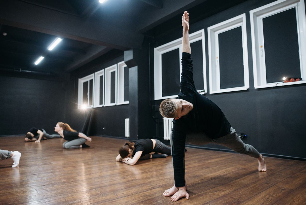 class-01 Participants engaged in yoga poses during a fitness class in a modern studio.
